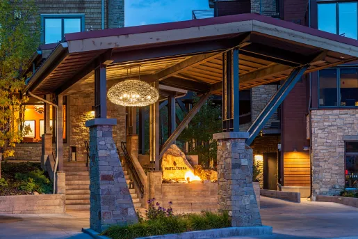Driveway entrance of hotel building with stone pillars and an illuminated sign