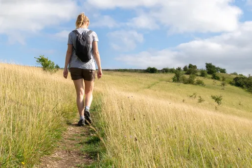 Woman walking through a field of tall weeds in a valley