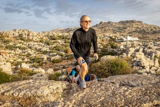 Man ascending a cliff with a large valley in the background