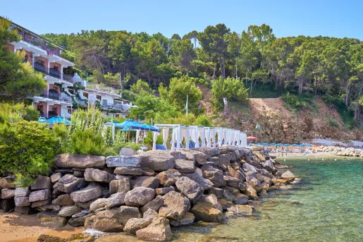 Outdoor patio of a hotel with a stone barricade leading to the ocean