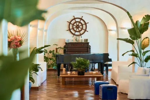 Room with beige couches and a piano in the back