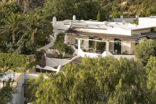 Hotel exterior of a white building surrounded by trees