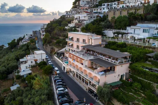 Exterior sky view of a peach-colored hotel building, with a long road in front