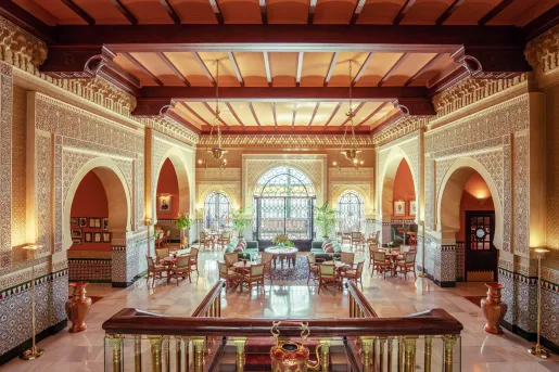 Hotel lobby with a large flight of stairs leading to tables and large windows