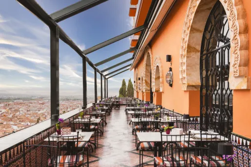 Outdoor patio with tables and chairs, looking out towards a town