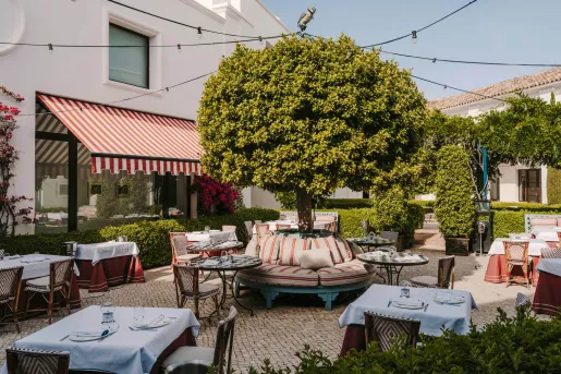 Outdoor patio with dining tables and trimmed trees