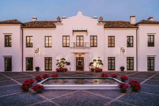 Exterior, outdoor view of large white building with a fountain in front