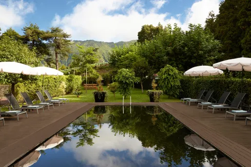 Outdoor pool with wooden walkways and a garden in the background