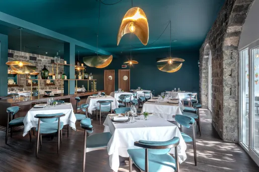 Dining hall with square, white tables and teal chairs