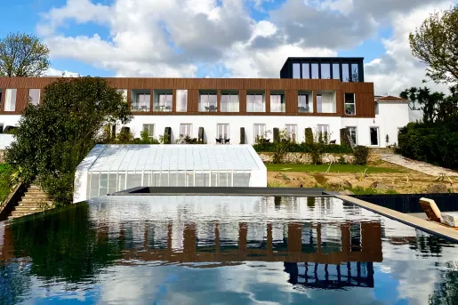 Exterior view of white and wooden building, with outdoor pool
