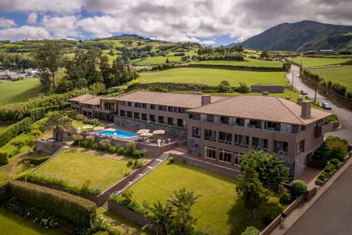 Exterior, sky view of beige hotel building wit large grass fields surrounding the building