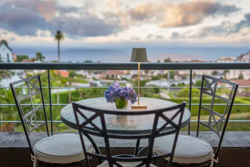 Outdoor balcony with a small circular table and 3 stools