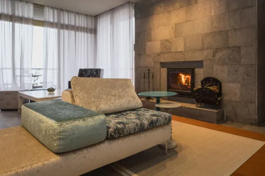 Corner room with cushioned, velvet couches in front of a stone fireplace