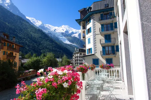 Exterior view of white and blue hotel building, with large mountains in the distance