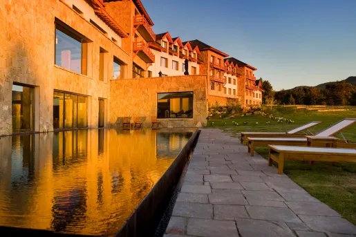 Exterior view of hotel building with an outdoor pool, and large grass area