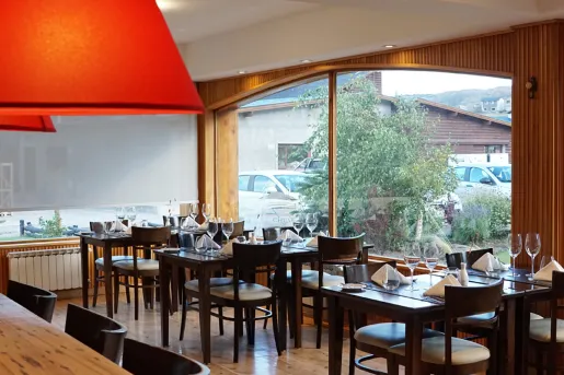 Restaurant dining room with wooden tables and chairs, with large windows to the right