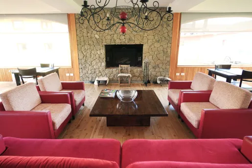 Lounge with red cushioned chairs and a stone wall in the back