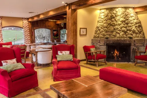 Lounge and seating area, with red cushioned chairs and a stone fireplace