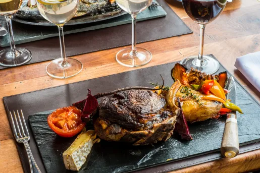 Black plate with roasted meat and vegetables