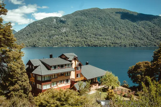 Exterior view of multi-level building with a hills in the background and a lake