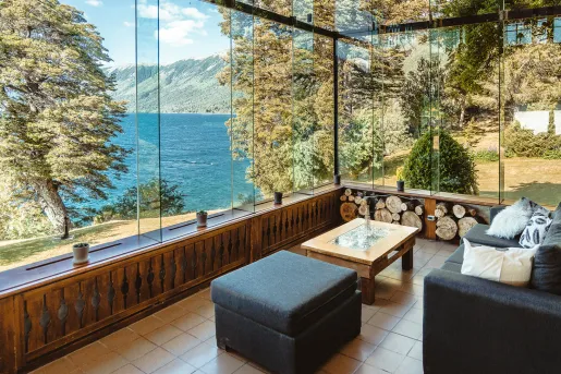 Indoor seating area with large glass walls looking out to a lake