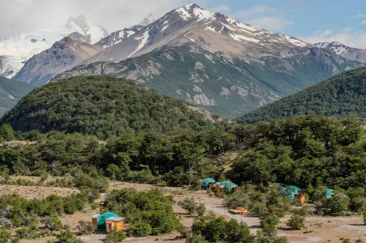Large valley with small dome huts, and large trees in the background