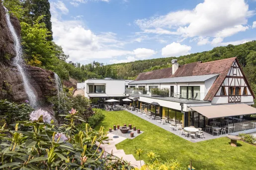 Exterior view of hotel building with an outdoor patio and a small waterfall