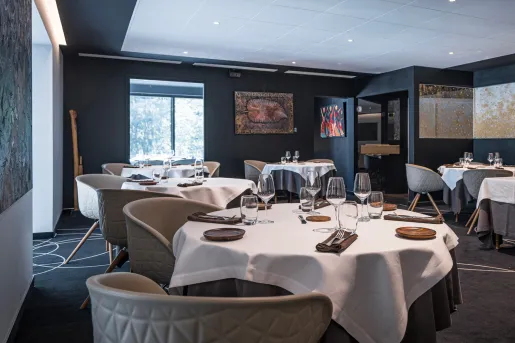 Restaurant dining room with multiple, circular tables and wine glasses on each table