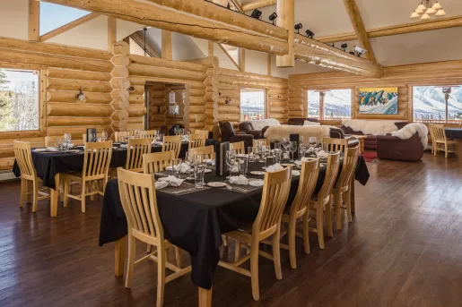Dining hall in a cabin, with wooden chairs around black dining tables