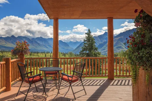 Outdoor patio with metal chairs and tables, with views of a forest