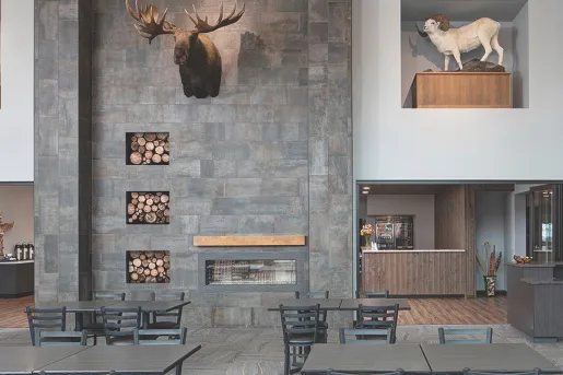 Restaurant dining hall with large stone walls and black dining tables