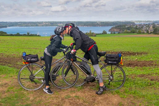 Man and woman standing over their bikes, kissing each other
