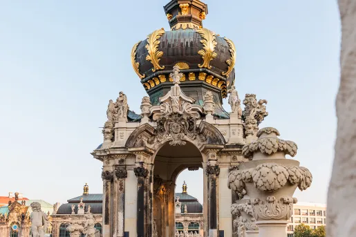 White, green and gold palace-like structure with larger buildings in the background