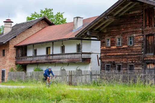 Man riding a bike on an empty road with wooden houses in the background