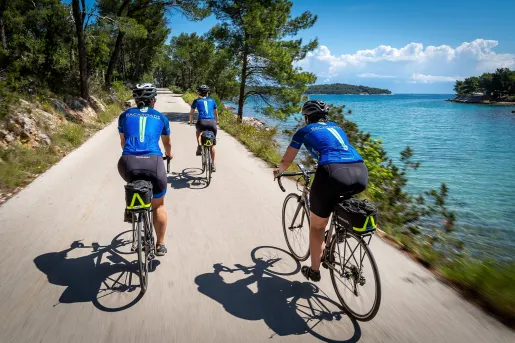 Group of people riding bikes on a path, with the ocean to the right