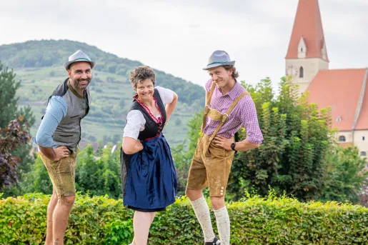 Two men and one woman wearing traditional Dutch clothing, smiling with hands on their hips
