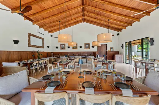 Restaurant dining hall with wooden tables and cushioned chairs, and circular light fixtures