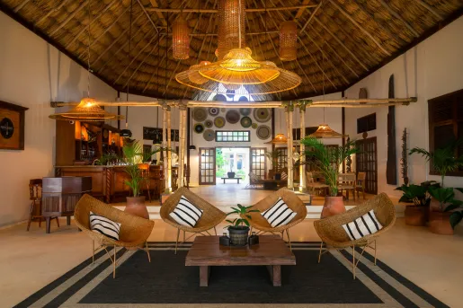 Large bar and lounge with straw chairs and a wooden table in the center