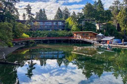 Exterior view of large hotel building with a lake and wooden bridge in front