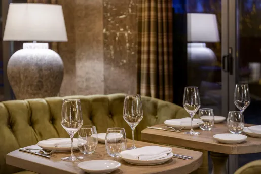 Two small tables with plates and handkerchiefs, with glasses on wine