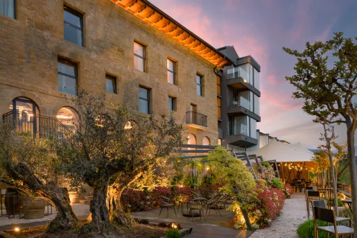 Exterior view of brick, multi-story building with a garden patio in front