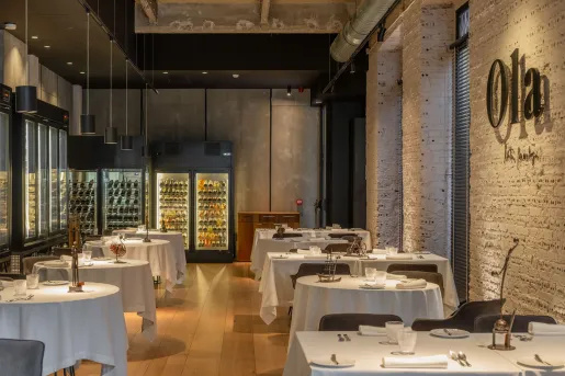 Indoor dining hall with circular, white dining tables and stone walls