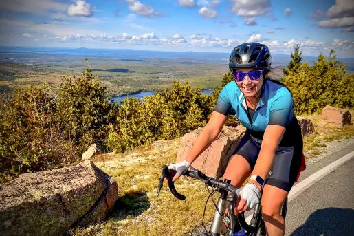 Woman wearing biking gear, smiling and riding her bike