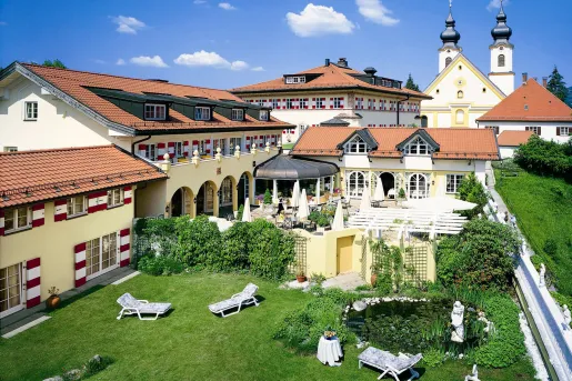 Exterior view of beige hotel building, with a patio and garden to the right