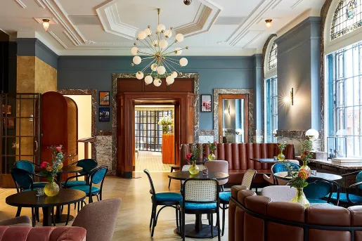 Hotel lounge and seating area with cushioned sofas and chairs, in front of circular tables