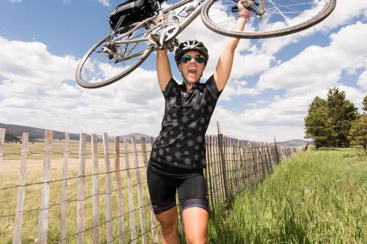Woman smiling while carrying her bike above her head