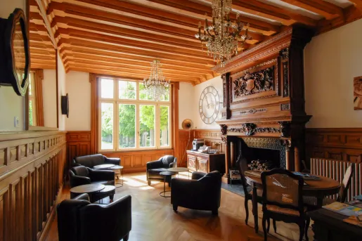 Lounge room with wooden fireplace and large, leather chairs
