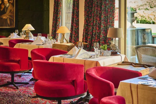 Dining area with beige, square tables and red, cushioned chairs