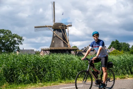 Man riding a bike with a windmill in the background