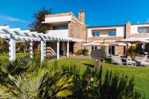 Exterior view of stone and white building with a garden and grass area in front